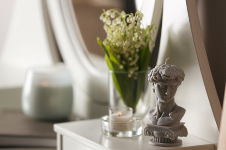 Beautiful David bust candle and flowers on table indoors, space for textの写真素材