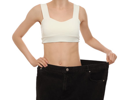 Young woman wearing big jeans after weight loss on white background, closeupの写真素材