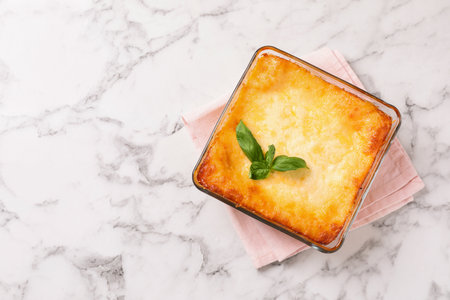 Tasty cooked lasagna in baking dish on white marble table, top view. Space for textの写真素材