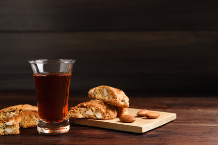 Tasty cantucci and glass of liqueur on wooden table, space for text. Traditional Italian almond biscuitsの写真素材