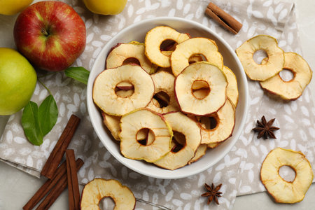 Delicious apple chips, fresh fruits, anise and cinnamon on light gray table, flat layの写真素材