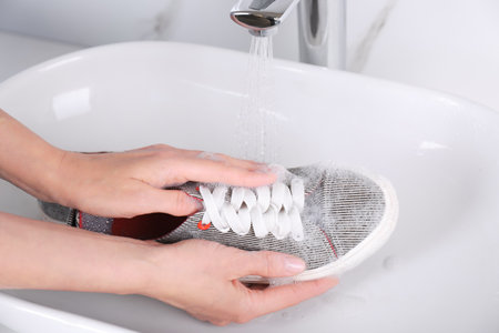 Woman washing sport shoe in sink, closeupの写真素材