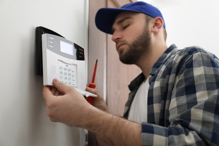 Man installing home security system on white wall in roomの写真素材