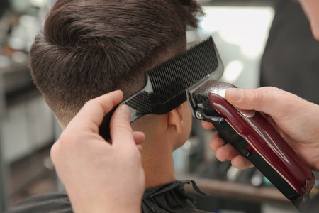Professional barber making stylish haircut in salon, closeupの写真素材