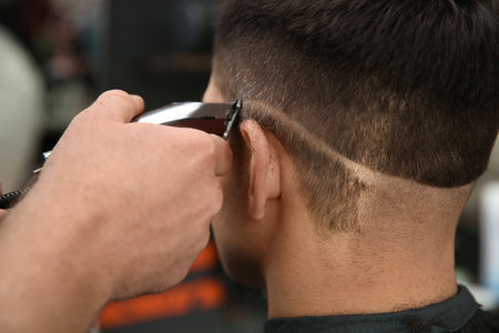Professional barber making stylish haircut in salon, closeupの写真素材