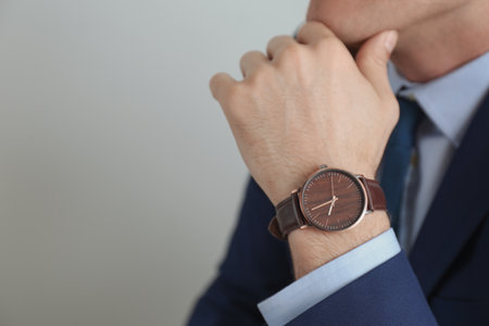 Businessman with luxury wrist watch on gray background, closeup. Space for textの写真素材