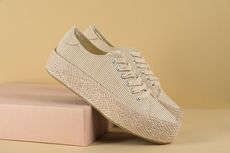 Pair of stylish sneakers on beige backgroundの写真素材