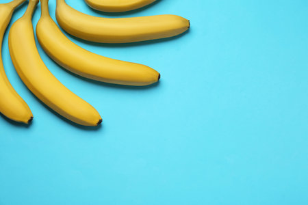 Ripe yellow bananas on turquoise background, flat lay. Space for textの写真素材