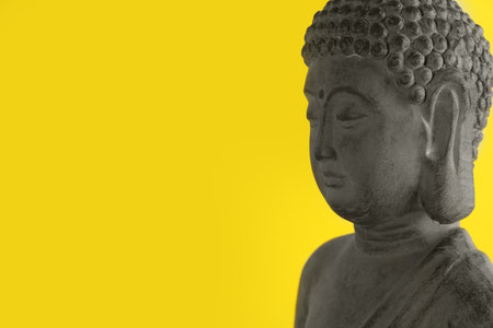 Beautiful stone Buddha sculpture on yellow background. Space for textの写真素材