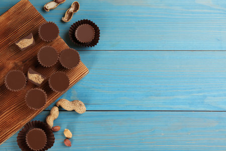 Flat lay composition with delicious peanut butter cups on light blue wooden table, space for textの写真素材