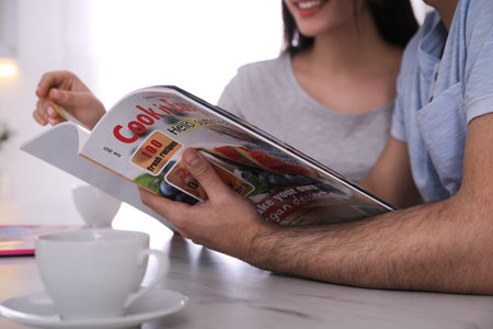 Couple reading magazine at table in kitchen, closeupの写真素材