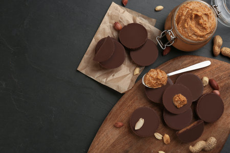 Flat lay composition with delicious peanut butter cups on black table, space for textの写真素材