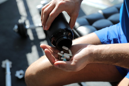 Sportsman with bottle of pills in gym, closeup. Doping conceptの写真素材