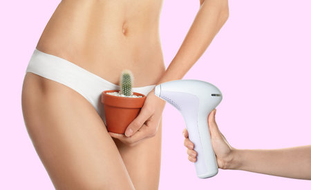 Hair removal concept. Lady with cactus and woman holding photoepilator on pink background, closeupの写真素材