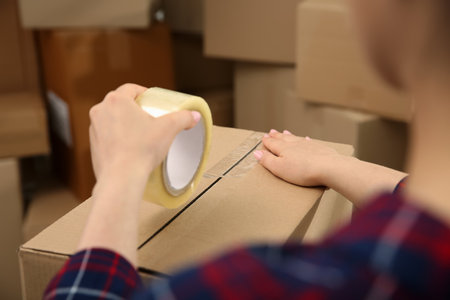 Woman tapping cardboard box indoors, closeup viewの写真素材