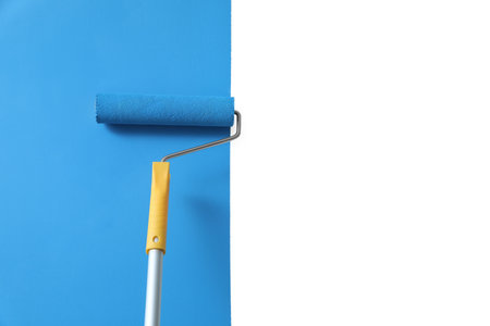 Applying light blue paint with roller brush on white wallの写真素材