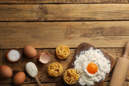 Raw noodles and ingredients on wooden table, flat lay. Space for textの写真素材