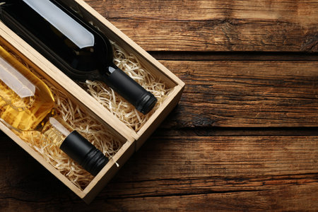 Boxes with bottles of wine on wooden background, flat lay. Space for textの写真素材