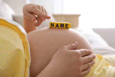 Pregnant woman with cubes on belly indoors, closeup. Choosing baby nameの写真素材
