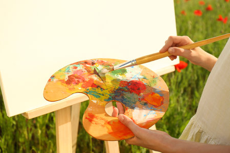 Little girl painting on easel in countryside, closeupの写真素材