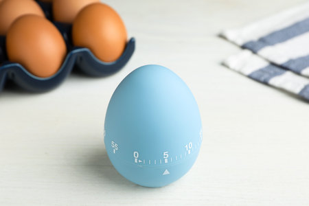 Kitchen timer and eggs on white tableの写真素材
