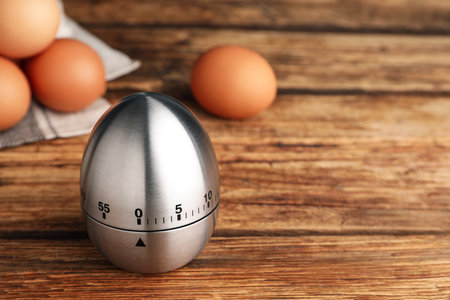Kitchen timer and eggs on wooden table. Space for textの写真素材