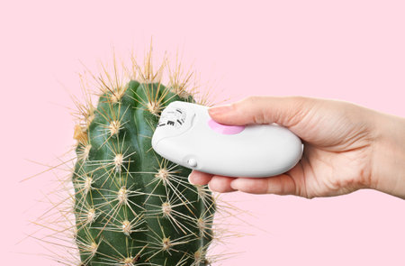 Hair removal concept. Cactus and woman holding epilator on pink background, closeupの写真素材