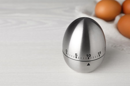 Kitchen timer and eggs on white wooden table. Space for textの写真素材