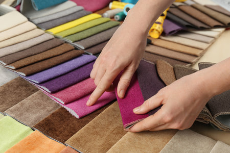 Woman choosing among colorful fabric samples, closeup