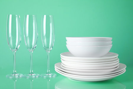Set of clean tableware on light green backgroundの写真素材