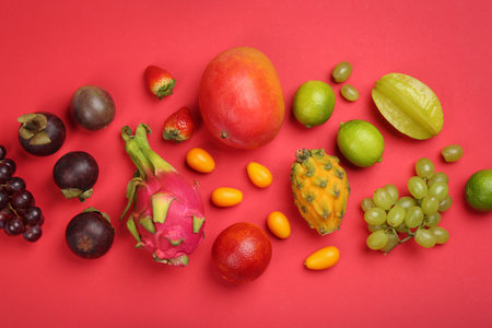 Many different delicious exotic fruits on red background, flat layの写真素材