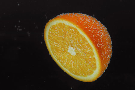 Half of orange in sparkling water on black background. Citrus sodaの写真素材