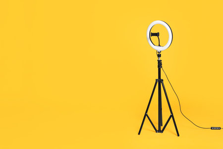 Modern tripod with ring light on yellow background. Space for textの写真素材