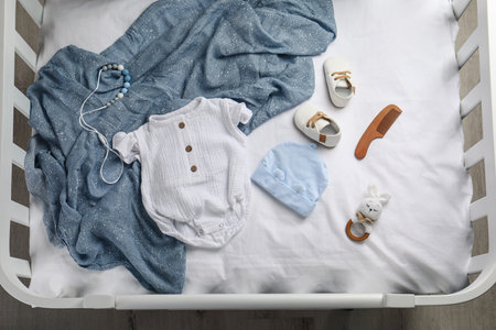 Flat lay composition with cute baby clothes and accessories on white bedsheet in cribの写真素材