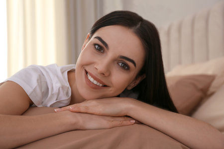 Young woman lying on bed with brown lines at homeの写真素材