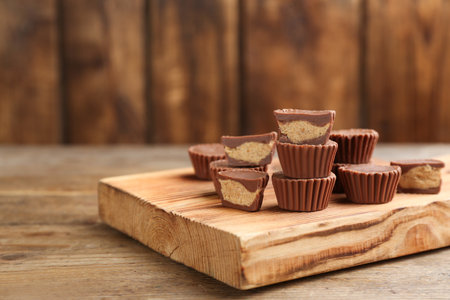 Delicious peanut butter cups on wooden table, space for text