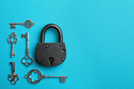 Padlock and beautiful vintage keys on light blue background, flat lay. Space for textの写真素材