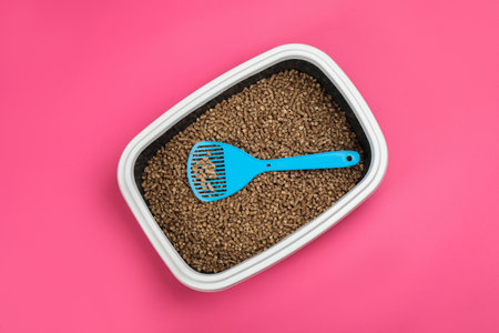 Cat litter tray with filler and scoop on pink background, top viewの写真素材