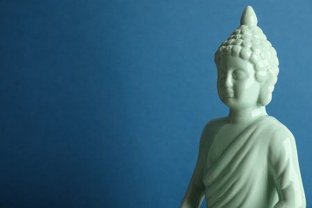 Beautiful ceramic Buddha sculpture on blue background. Space for textの写真素材