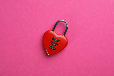 Red heart shaped combination lock on pink background, top viewの写真素材