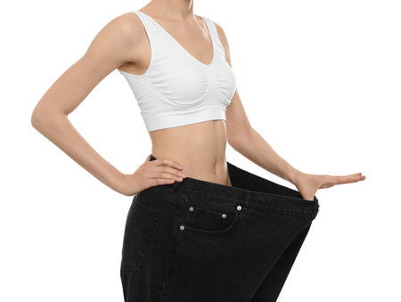 Young woman wearing big jeans after weight loss on white background, closeupの写真素材
