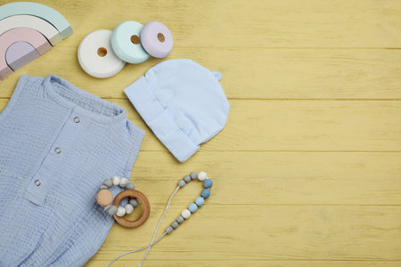Flat lay composition with baby clothes and accessories on yellow wooden table. Space for textの写真素材