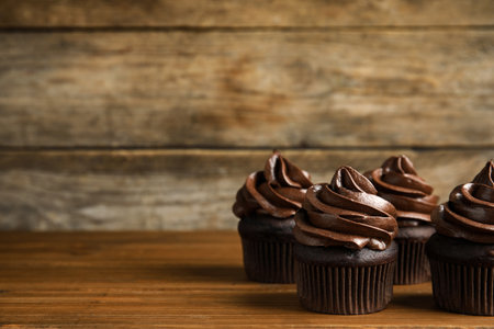 Delicious chocolate cupcakes with cream on wooden table. Space for textの写真素材