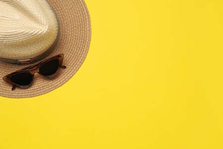 Hat and sunglasses on yellow background, flat lay with space for text. sun protectionの写真素材