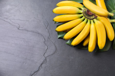 Tasty ripe baby bananas on dark table, above view. Space for textの写真素材