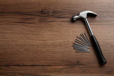 Hammer and metal nails on wooden table, flat lay. Space for textの写真素材
