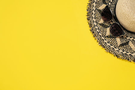 Straw hat and sunglasses on yellow background, flat lay with space for text. sun protectionの写真素材