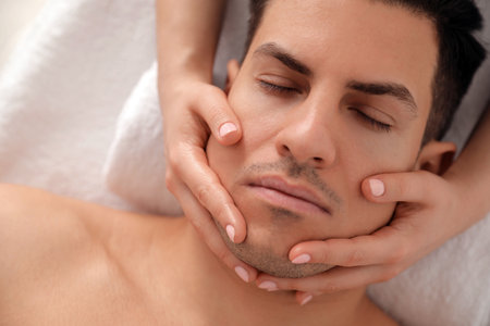 Man receiving facial massage in beauty salon, top viewの写真素材