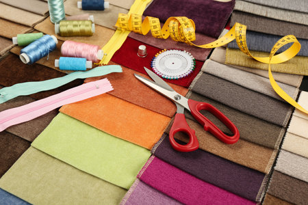 Different sewing accessories on colorful fabric samples