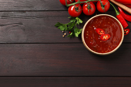 Spicy chili sauce and ingredients on wooden table, flat lay. Space for textの写真素材